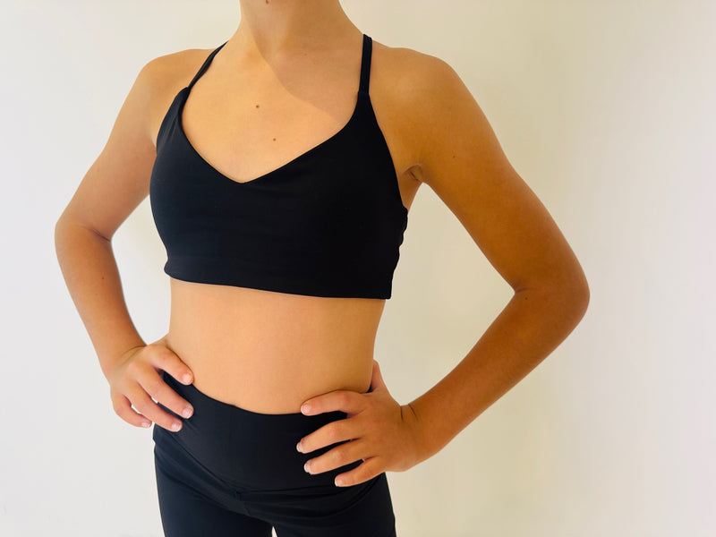 Person wearing a black sports bra and leggings against a plain background