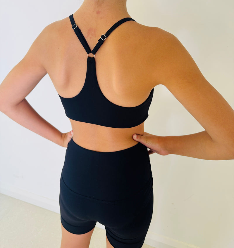 Person wearing a black sports bra and shorts on a plain background