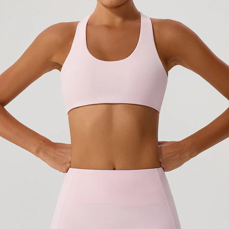 Person wearing a light pink sports bra and leggings on a plain background