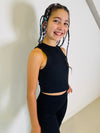 Person wearing a black sleeveless top and leggings against a neutral background